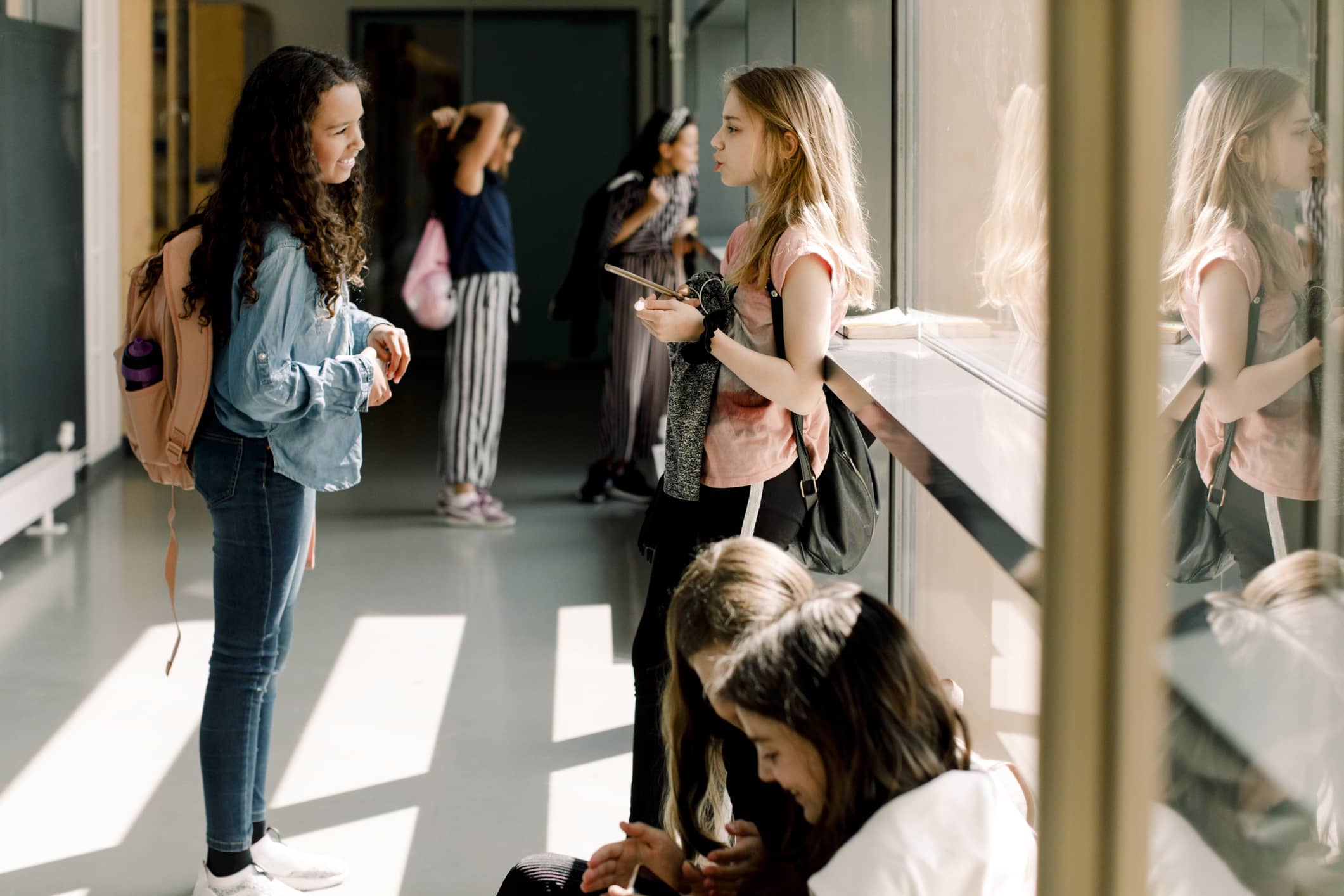 Students talking in front of window in school hallway